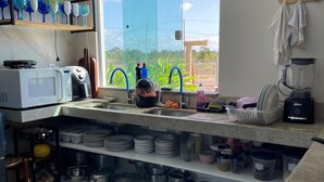 Une cuisine moderne dotée d’une grande fenêtre, d’un évier, d’un four à micro-ondes et de divers ustensiles de cuisine.