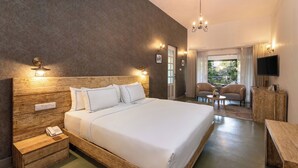 Une chambre d’hôtel avec un grand lit, des lampes de chevet, une table de nuit en bois, une petite table et un téléviseur fixé au mur.