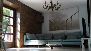 A modern living room with a light blue sofa, a small round table, and a chandelier. - Holiday Home Jan (Stara Novalja)