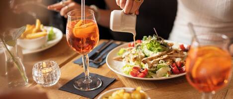 A dining table with a plate of food, a glass of drink, and a candle.