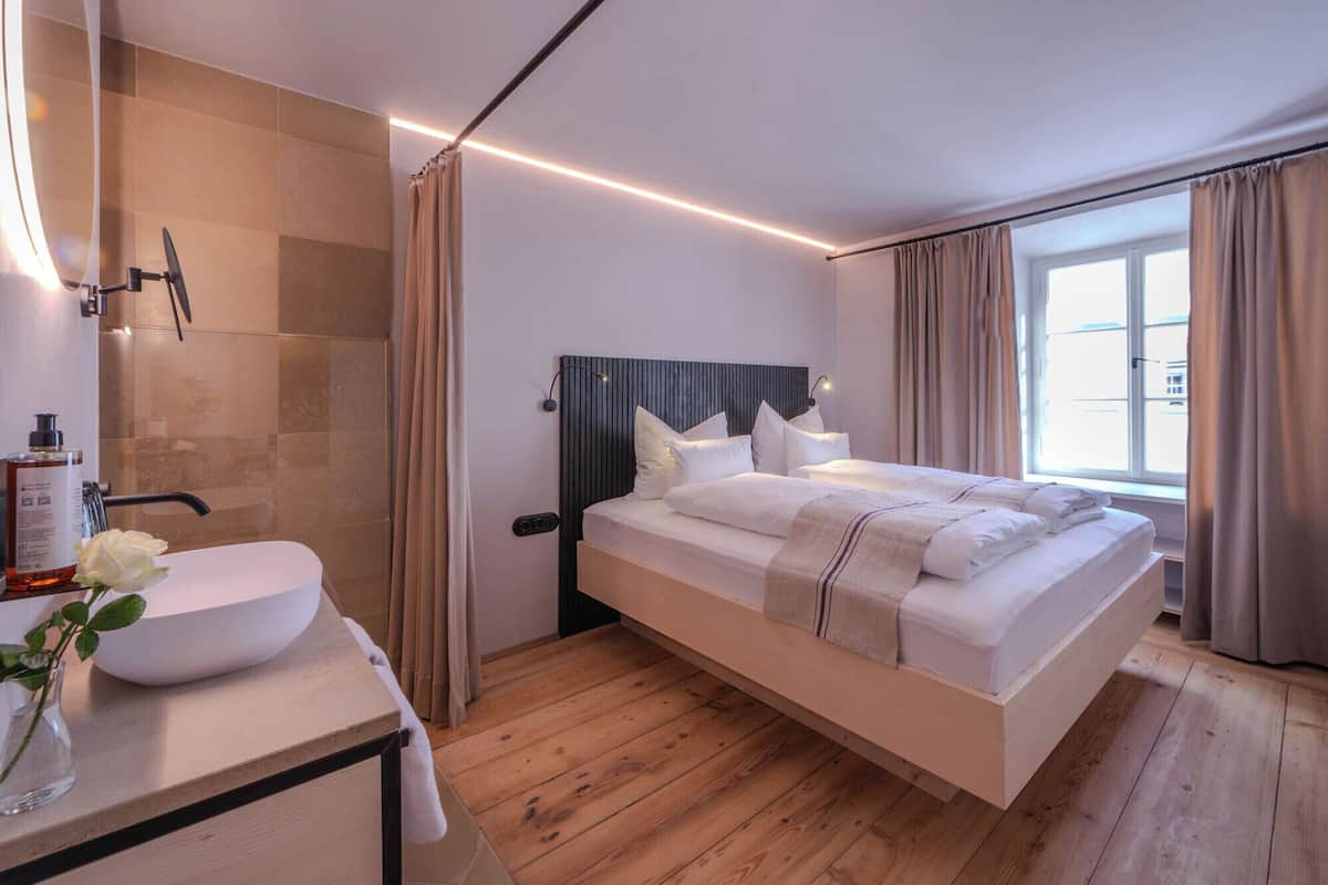 Ein modernes Schlafzimmer mit Bett, Nachttisch, Spiegel und Fenster.
