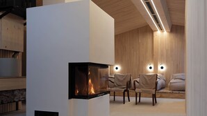 A modern interior with a fireplace, wooden panel walls, and a seating area with chairs and a sofa. - Hotel Kühbacher (Passau)