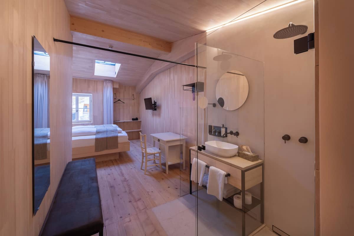 Ein modernes Badezimmer mit Duschkabine aus Glas, einer Holzbank und einem Nachttisch mit Stuhl.