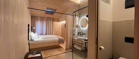 Un dormitorio moderno con techo de madera, cabina de ducha de vidrio, mesita de noche y una cama grande.