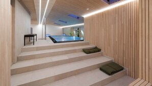 A modern interior with a wooden staircase leading to a spa area, including a hot tub and a seating area with cushions. - Hotel Kühbacher (Passau)