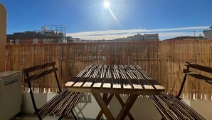 An outdoor patio with a wooden table and chairs, a ceiling fan, and a view of buildings in the background. - Savannah apartment near Carlton (Cannes)