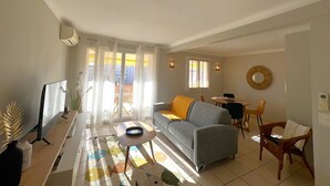A living room with a sofa, a coffee table, a TV, and a dining area with chairs. - Savannah apartment near Carlton (Cannes)