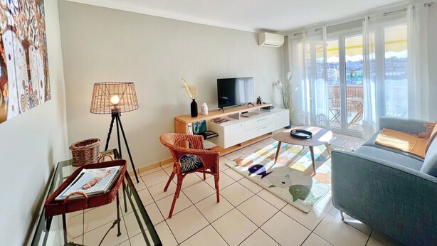 A modern living room with a sofa, a TV, a dining table with chairs, and a large window with a view. - Savannah apartment near Carlton (Cannes)
