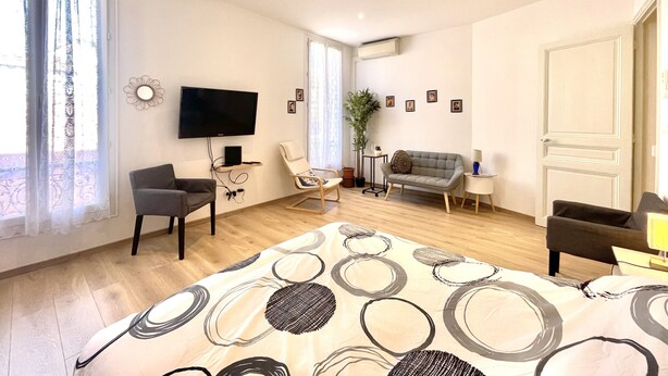 A modern bedroom with a large bed, a TV, a sofa, and a desk. - woody (Cannes)