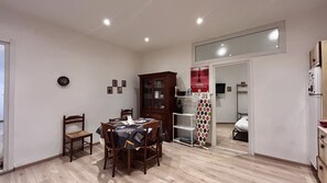Un comedor con una mesa preparada para dos, un armario de madera y un televisor al fondo.