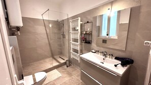 Une salle de bain moderne équipée d’une douche, de toilettes et d’un meuble-lavabo.