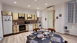 Cocina compacta con muebles de madera, horno empotrado, microondas y lavadora.
