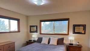 A bedroom with a large bed, two bedside tables, a dresser, and framed pictures on the walls.