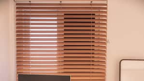 Une chambre d’hôtel équipée d’un grand téléviseur à écran plat posé sur un meuble, d’un petit bureau avec une machine à café et d’un miroir qui reflète le lit.