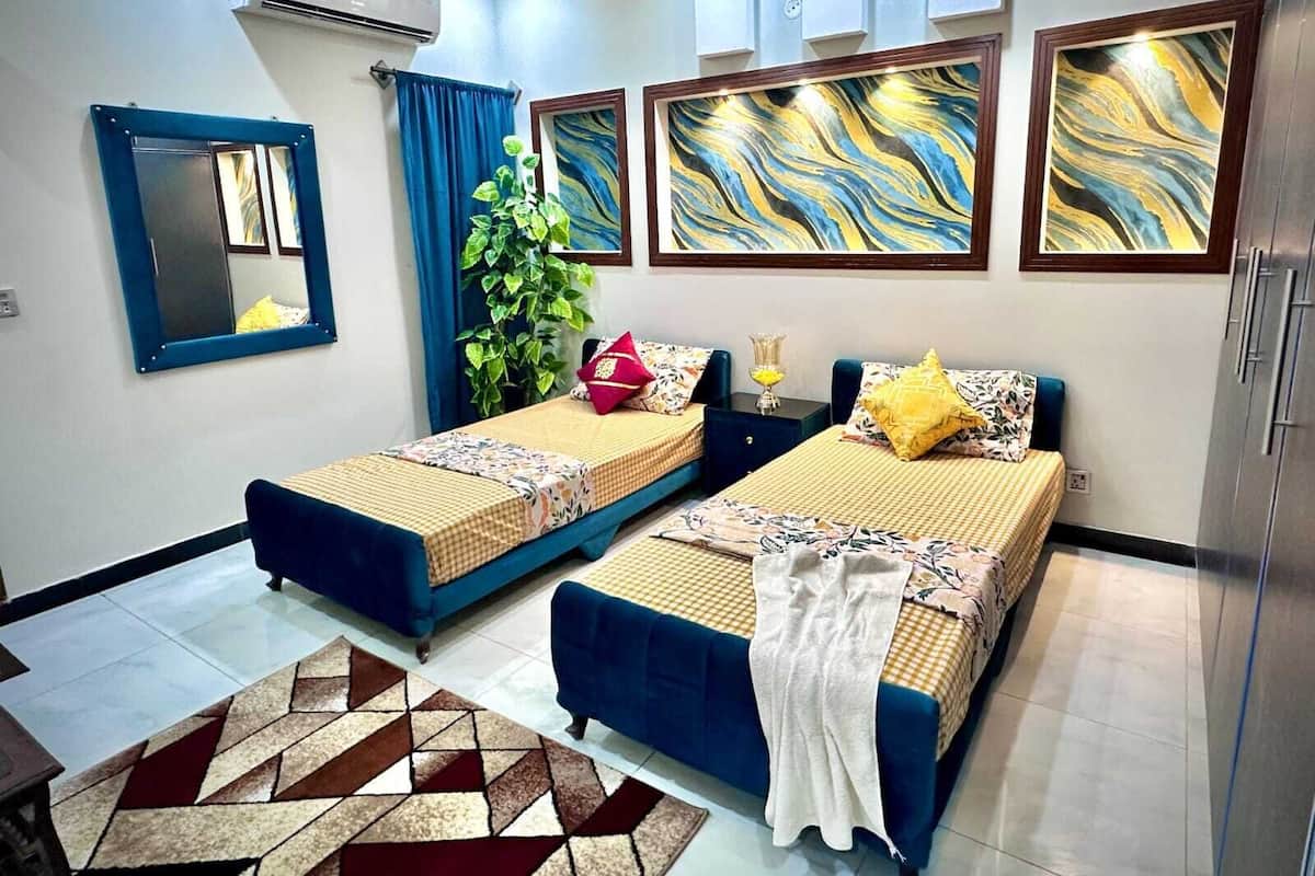 Ein Hotelzimmer mit zwei Betten, einem großen Spiegel und drei abstrakten Bildern an der Wand.