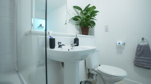 A modern bathroom with a white sink, a toilet, and a glass shower enclosure. - Central M K 1-bedroom Apartment, Sleeps 4, Parking (Milton Keynes)
