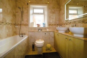 A bathroom with a bathtub, a toilet, a sink, and a window.