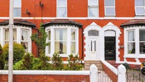 A red brick terraced house with white-framed windows and a black front door.
