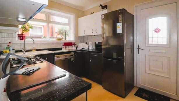 A modern kitchen with a black countertop, stainless steel appliances, and a white door.