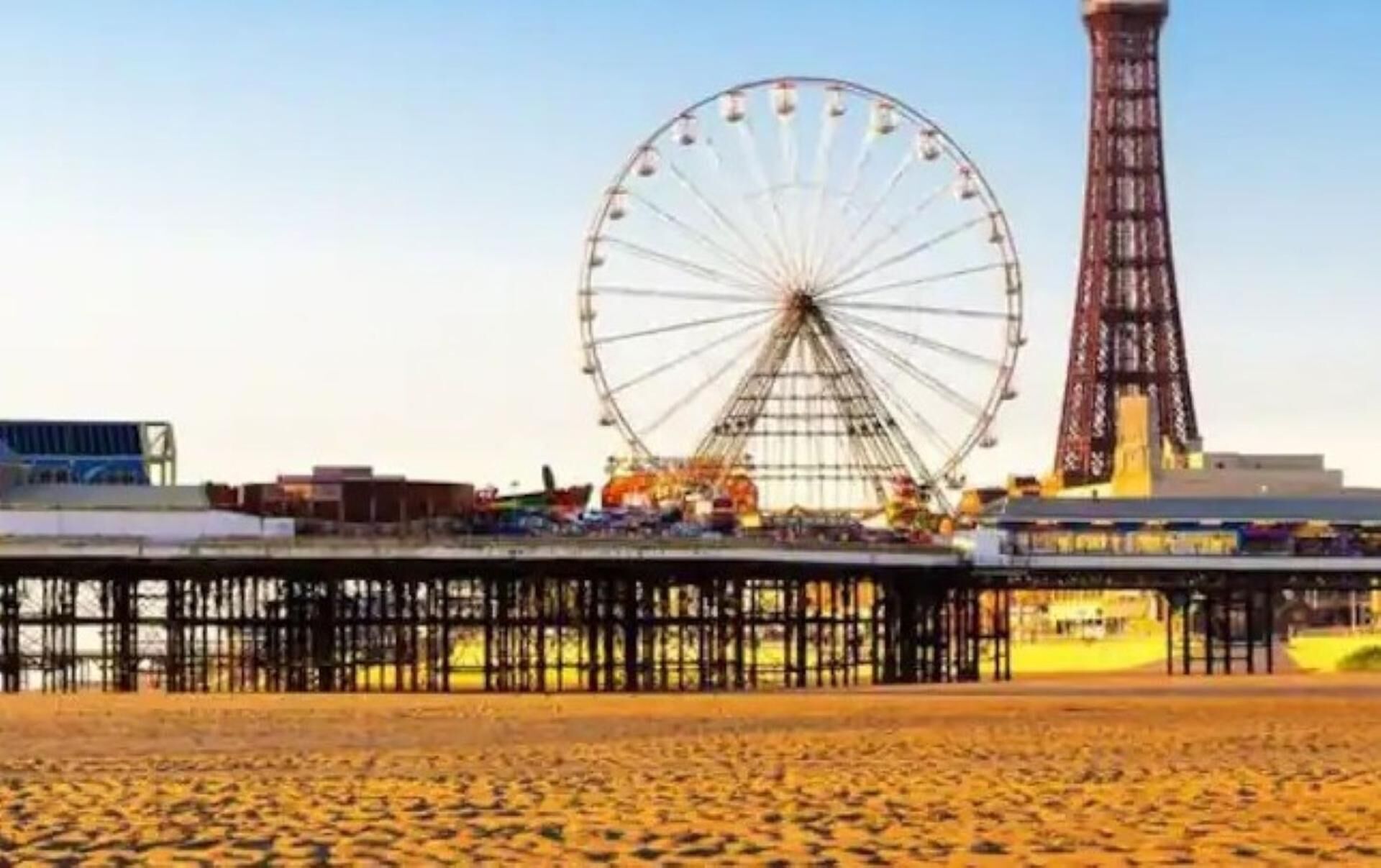 Une plage avec une jetée et une grande grande roue en arrière-plan.