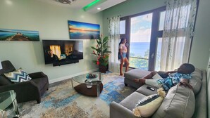 A living room with a large flat-screen TV, a sofa, a coffee table, and a potted plant. - Yellow Sands Luxury Villas Unit 1 (Castries)