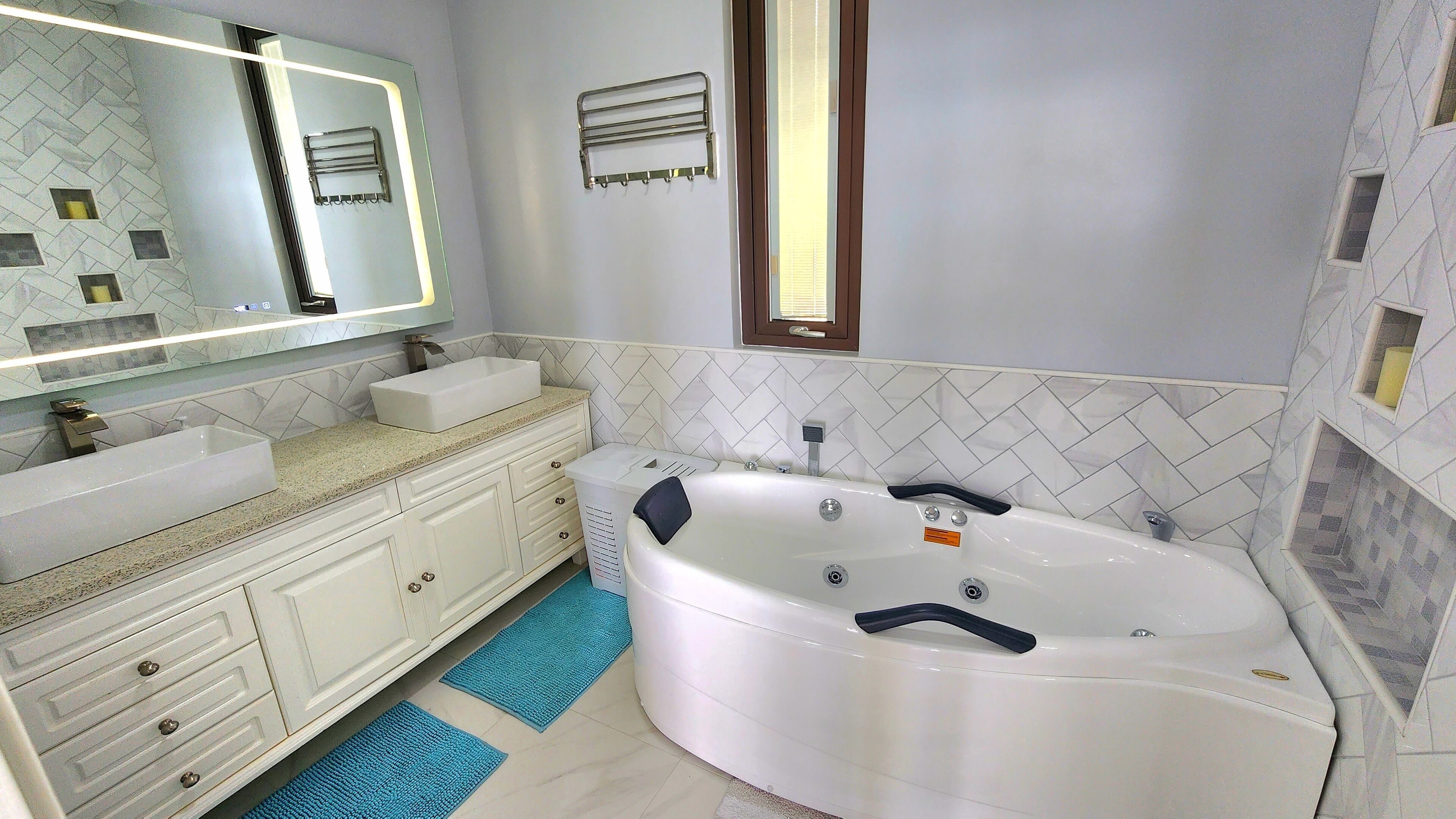 Un baño moderno con una bañera independiente, un espejo grande y un tocador con lavamanos.
