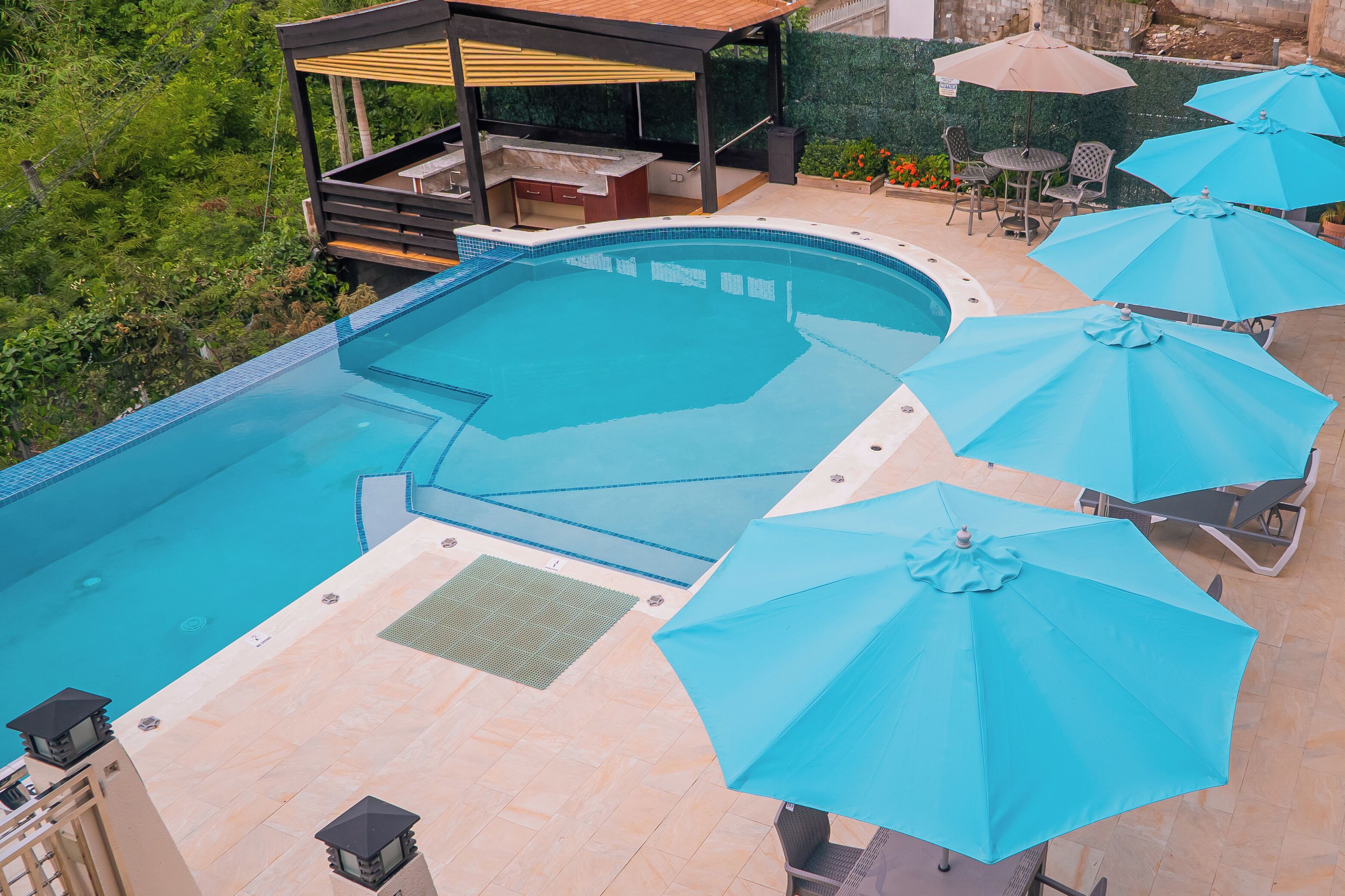 A swimming pool with a hot tub, outdoor seating, and umbrellas.