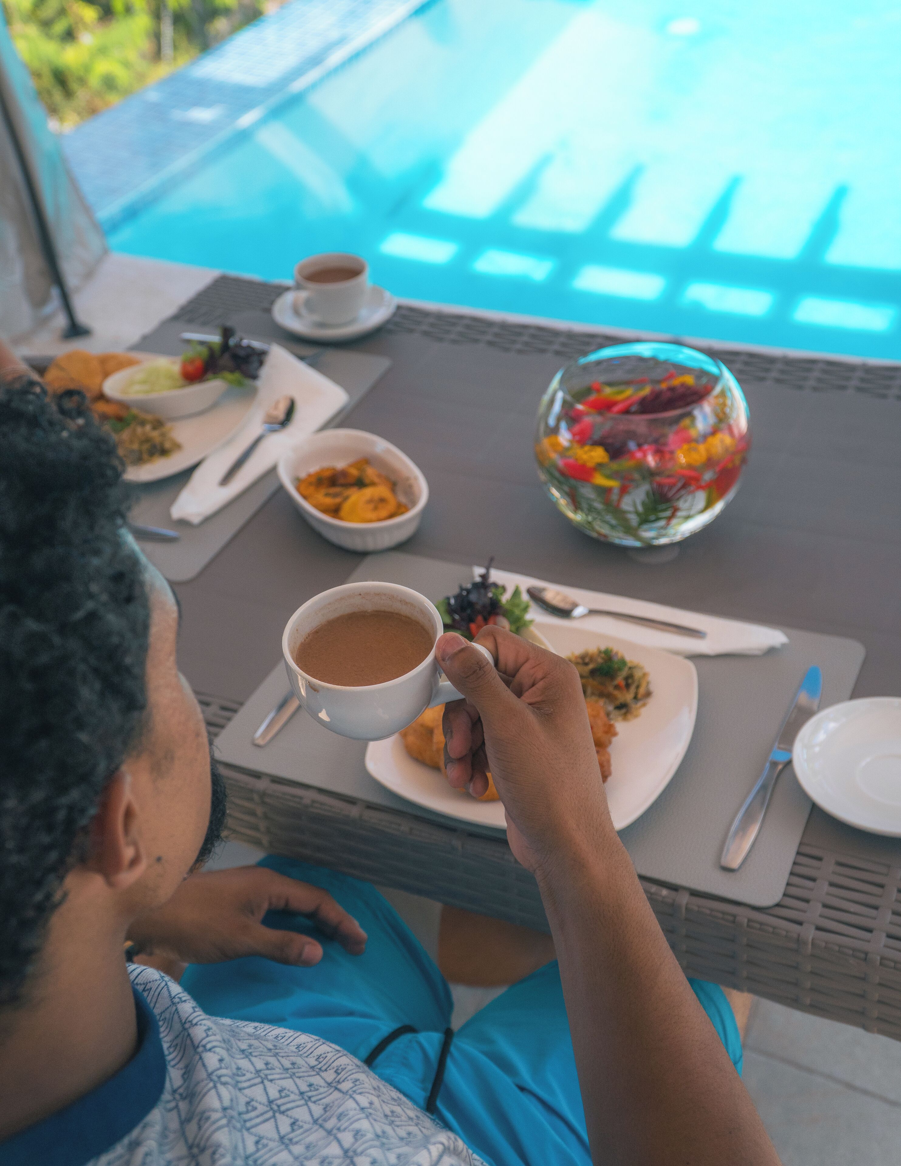 A dining table with plates of food, a cup of coffee, and a decorative glass bowl.