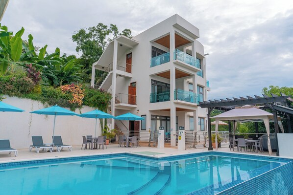 A modern hotel with a pool, outdoor seating, and a covered patio area. - Yellow Sands Luxury Villas Unit 1 (Castries)