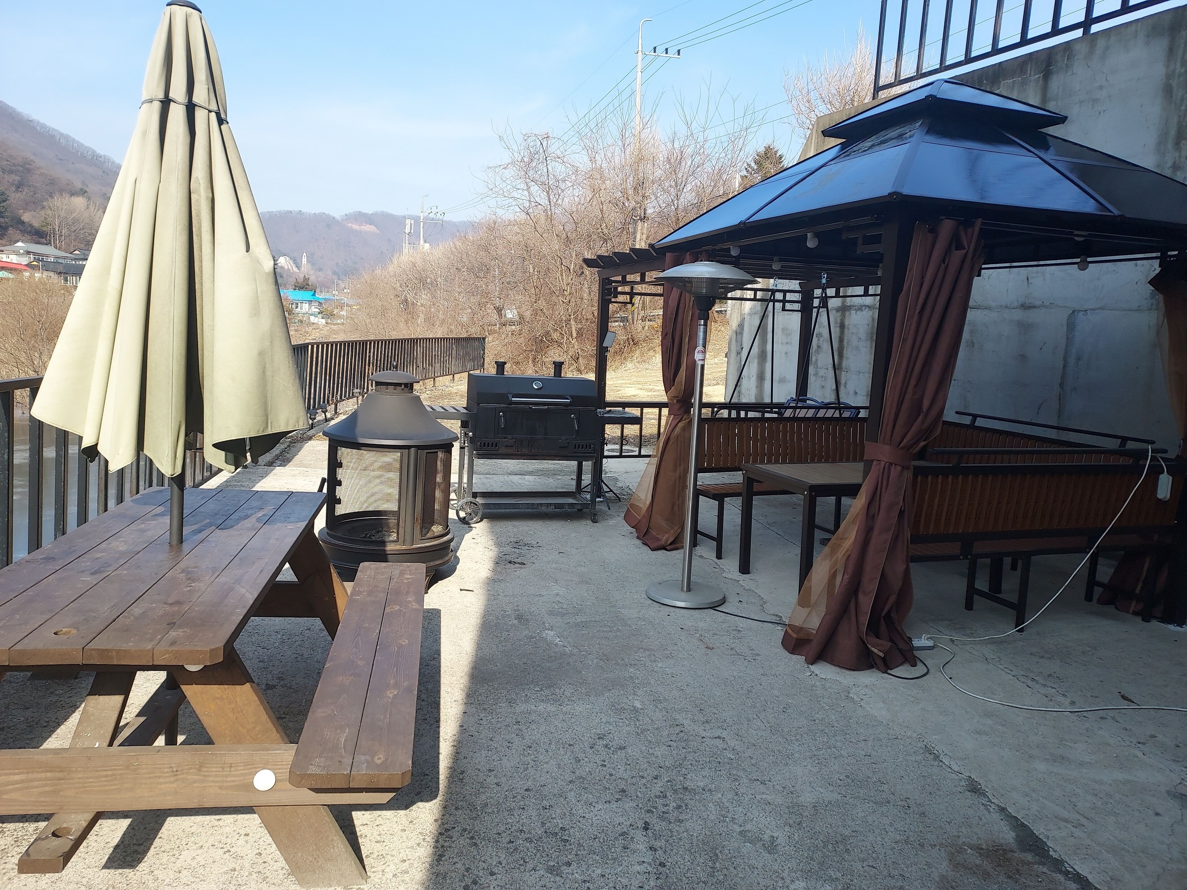 An outdoor patio with picnic tables, a grill, and a covered seating area.