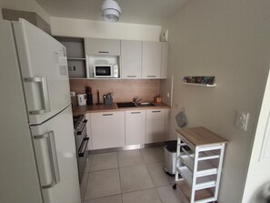 A compact kitchen with a microwave, sink, and a small trash bin.