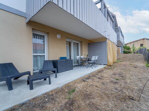 Ein modernes Wohngebäude mit einer überdachten Terrasse, die mit Gartenmöbeln und einem Tisch ausgestattet ist.