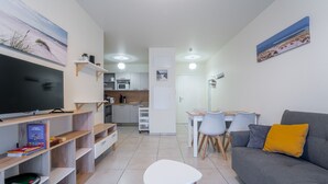 Una sala moderna con un sofá gris, un televisor de pantalla plana y un comedor con mesa y sillas.