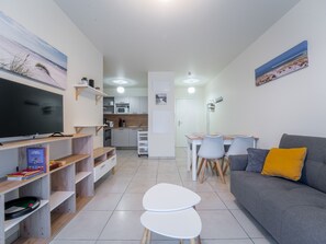 Un soggiorno moderno con un divano grigio, una televisione a schermo piatto e un'area pranzo con tavolo e sedie.