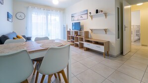 Una sala moderna con comedor, televisor y escalera que lleva a un dormitorio.