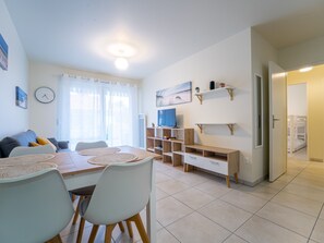 Un soggiorno moderno con zona pranzo, televisore e una scala che conduce a una camera da letto.