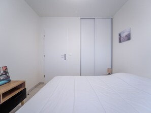 Un dormitorio con cama, armario, mesita de noche y lámpara de pared.