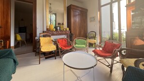 Ein Wohnzimmer mit Korbmöbelstühlen, einem runden Tisch und einem großen Spiegel.