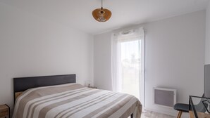 Un dormitorio con una cama, un escritorio y una ventana con cortinas.