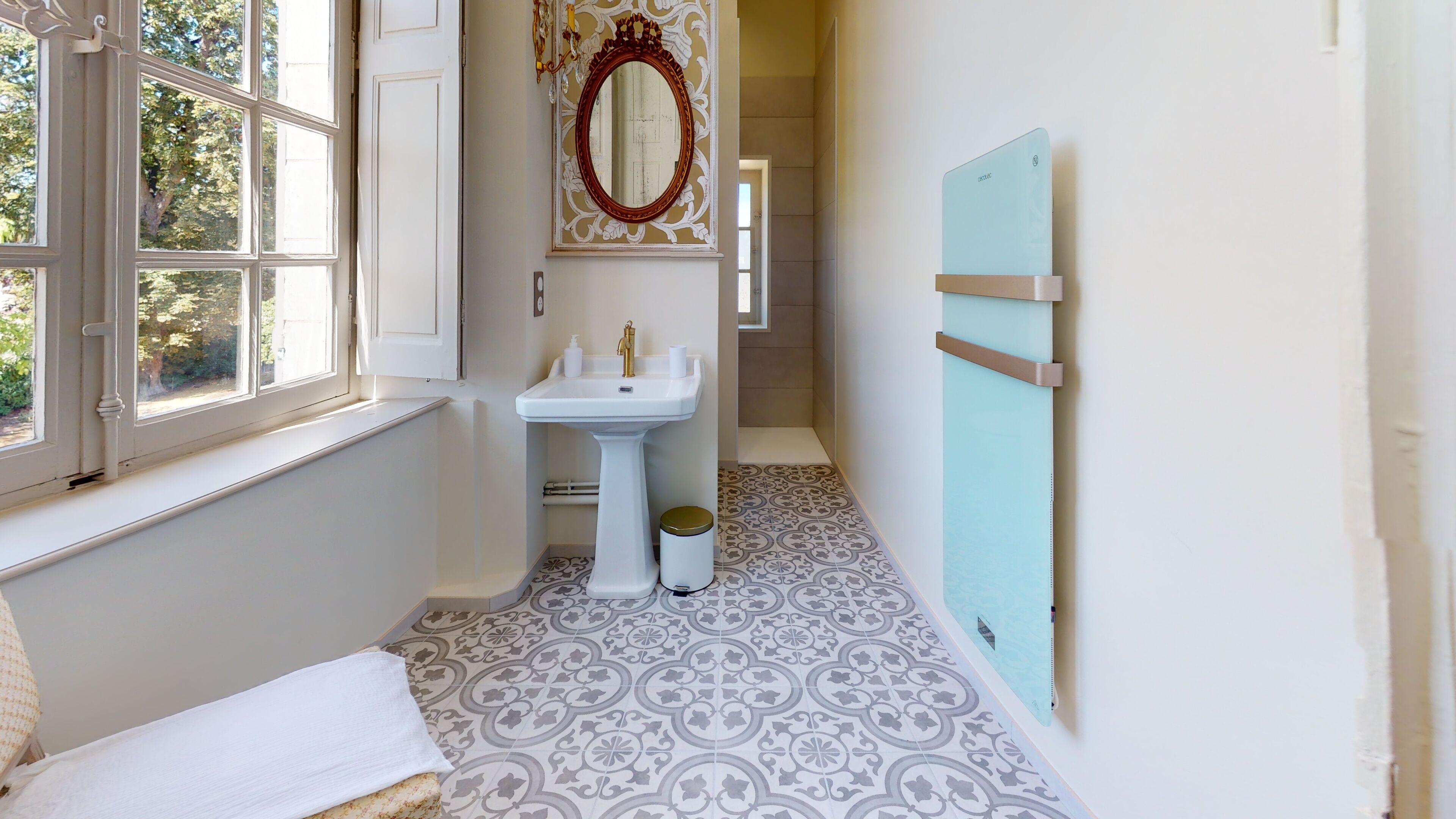 Un baño estrecho con ventana, un lavamanos, un espejo y un perchero azul.