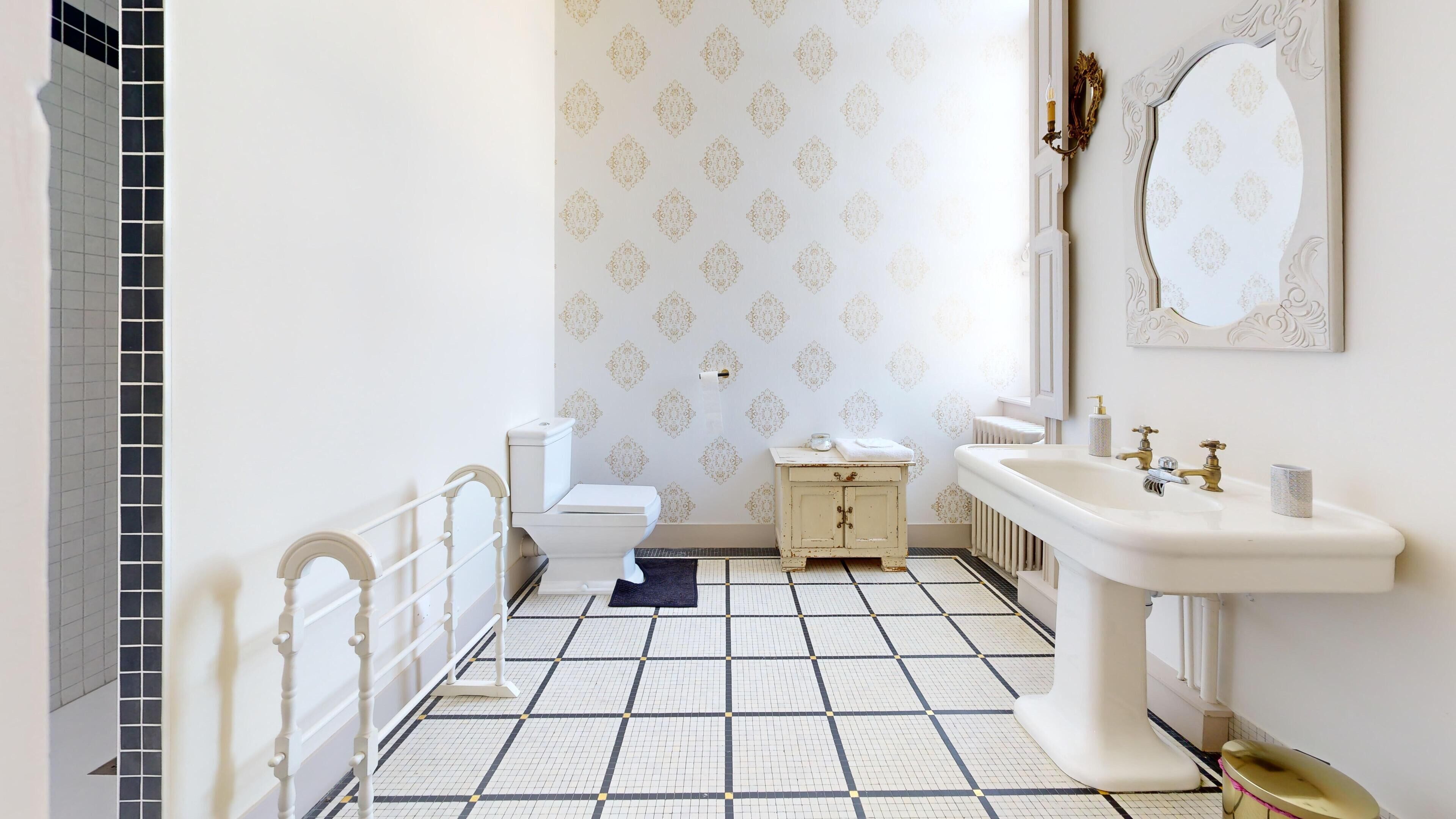 A bathroom with a toilet, a sink, and a mirror.
