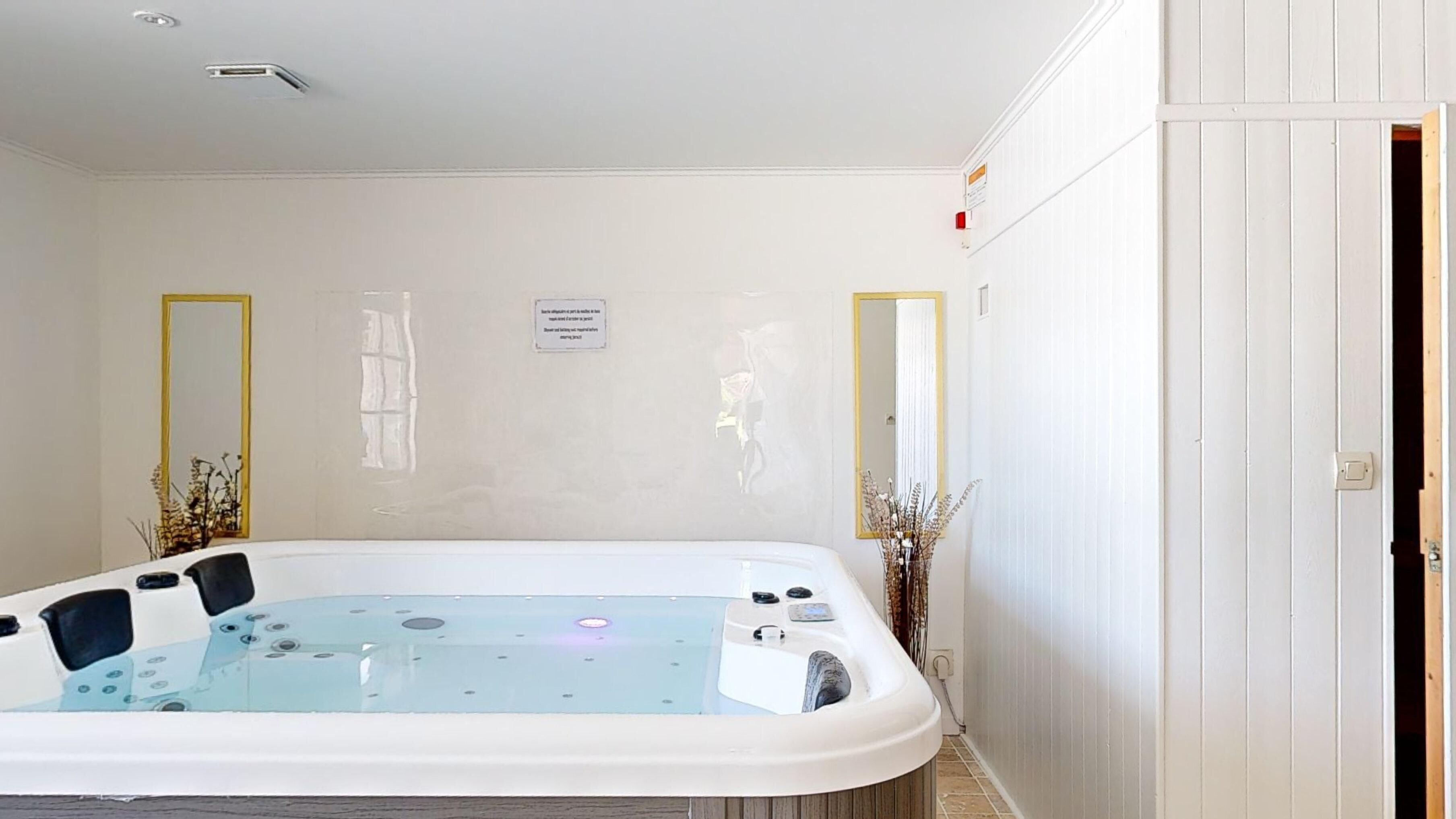 Un cuarto de spa con un jacuzzi, dos espejos y un cartel en la pared.