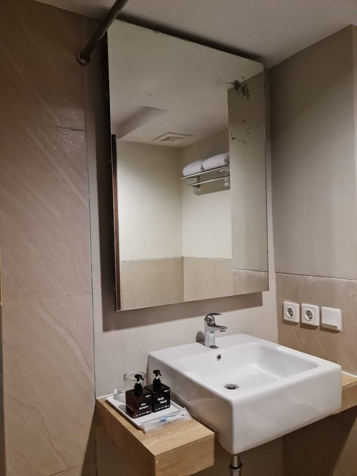 A bathroom with a white sink, a mirror, and a towel rack.