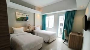A hotel room with two beds, a desk, a chair, a TV, and a window with curtains. - Bogor Icon Condotel by Holla (Bogor)