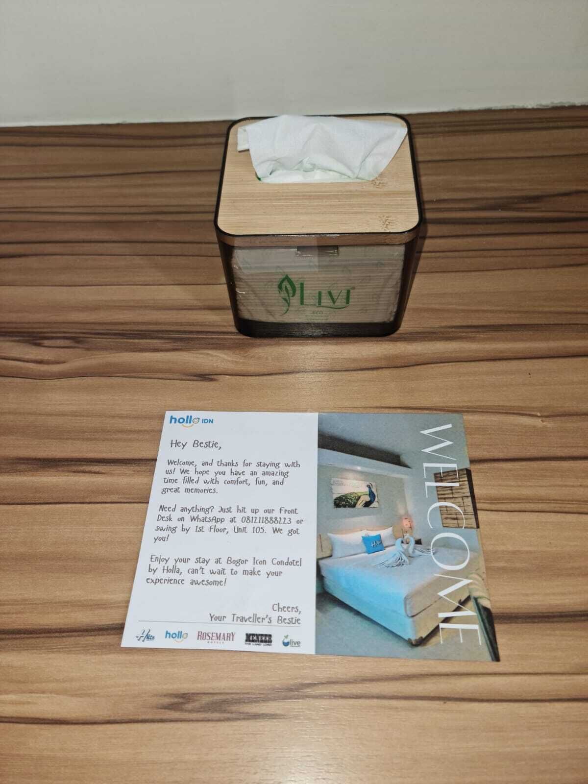 A wooden box with a tissue and a welcome card on a wooden surface.