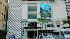 A modern building with a large glass entrance, a sign for a marketing gallery, and a parking sign for the lobby hotel. - Bogor Icon Condotel by Holla (Bogor)