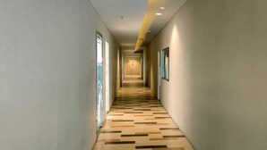 A long, narrow hallway with a patterned wooden floor and recessed lighting. - Bogor Icon Condotel by Holla (Bogor)
