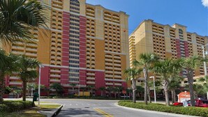 A multi-story hotel with a central atrium, balconies, and palm trees.