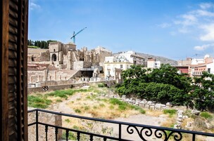 Vista de ruinas antiguas con edificios modernos al fondo.