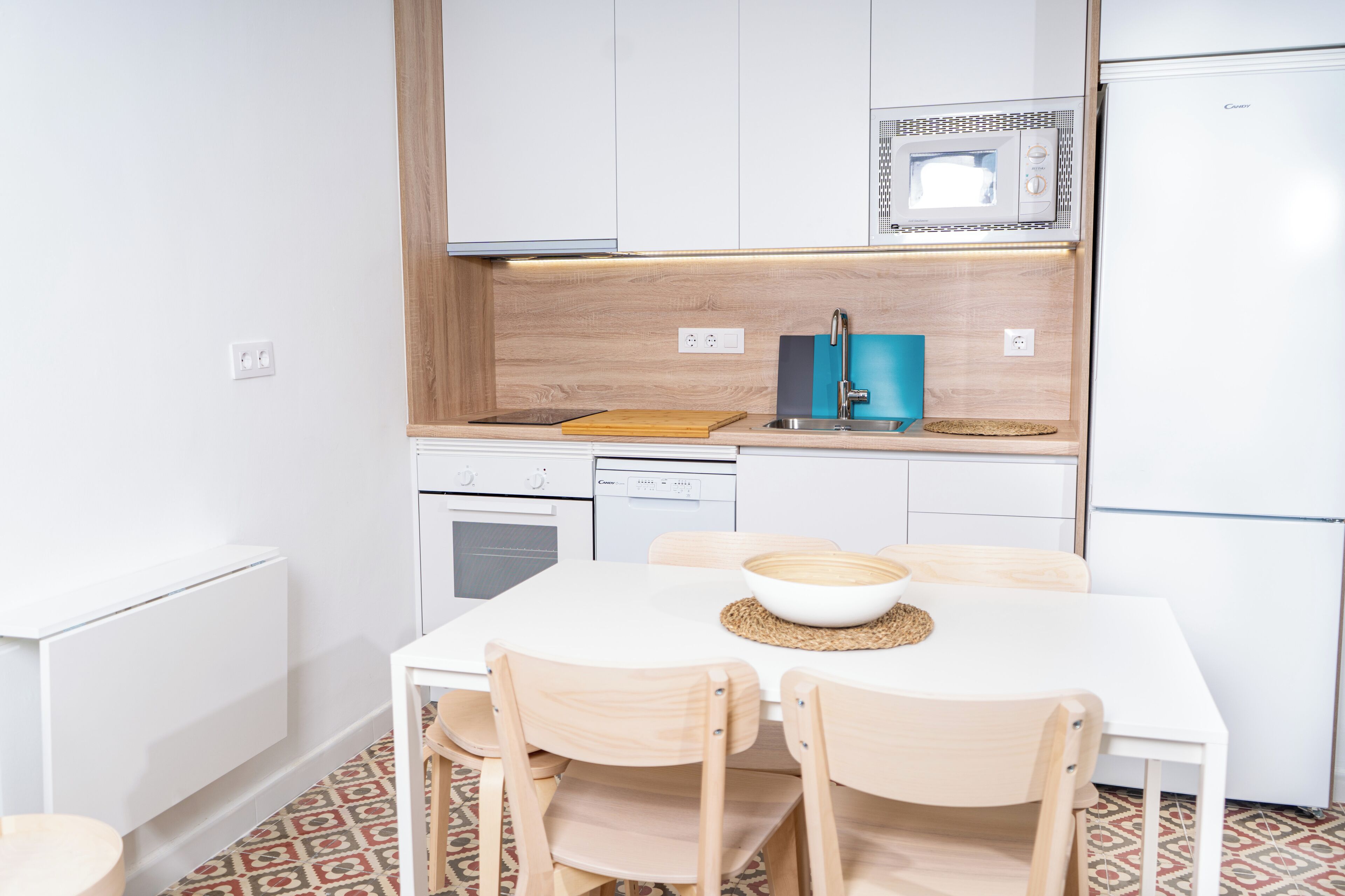 A modern kitchen with white cabinets, a microwave, a sink, and a dining table with chairs.